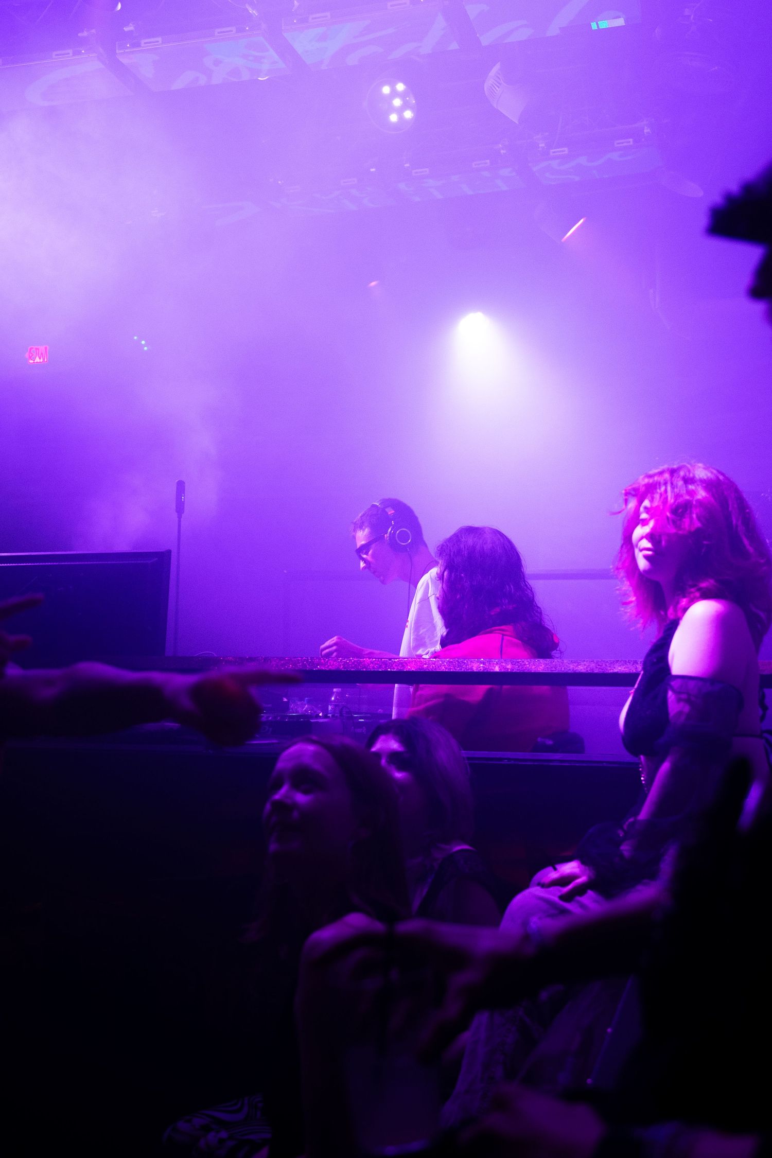 Crowd silhouettes against purple stage lighting at a nightclub performance.
