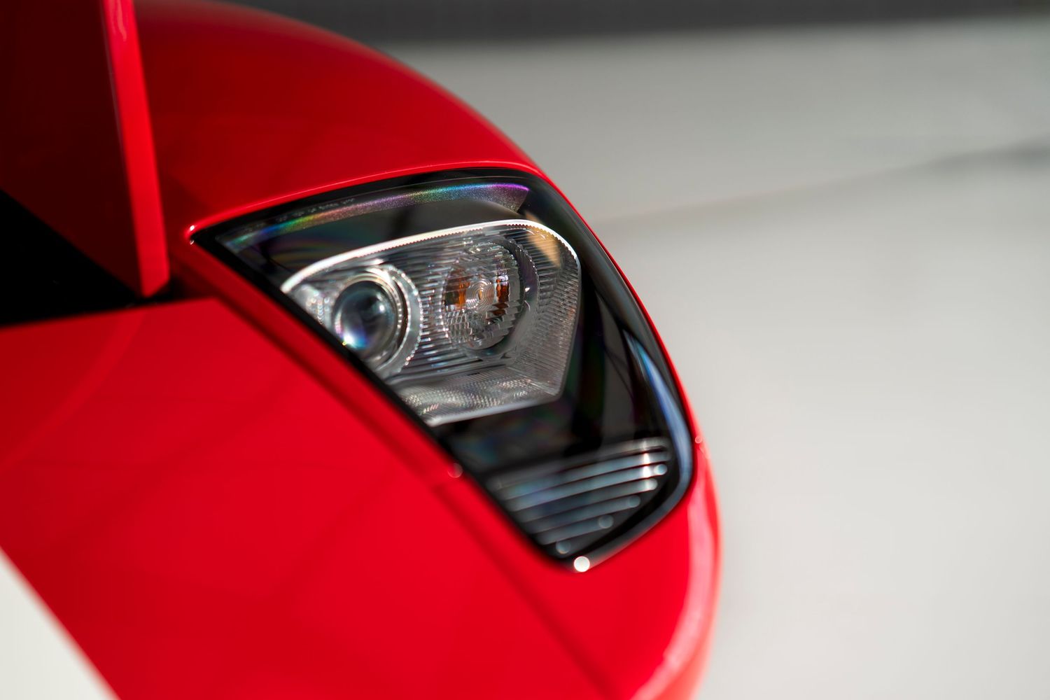 Sleek headlight design detail on a red sports car.