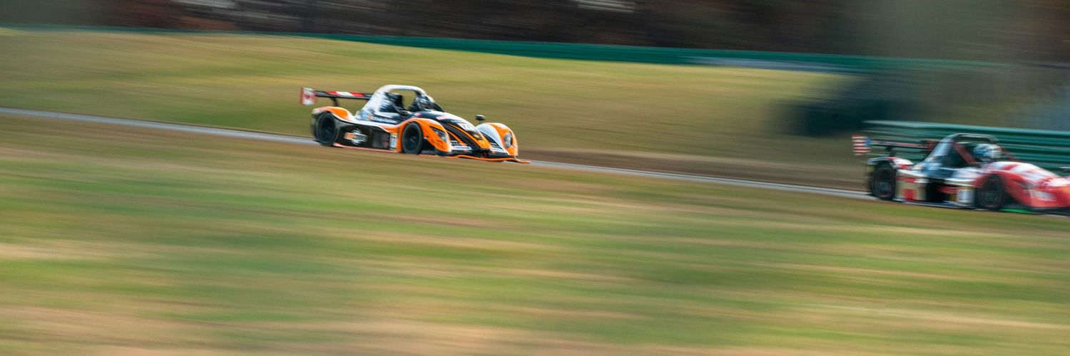 Race cars competing on a professional circuit during golden hour lighting.