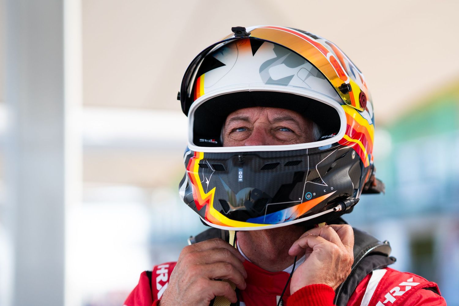 Race car drivers in helmets prepare for competition at a motorsport event.