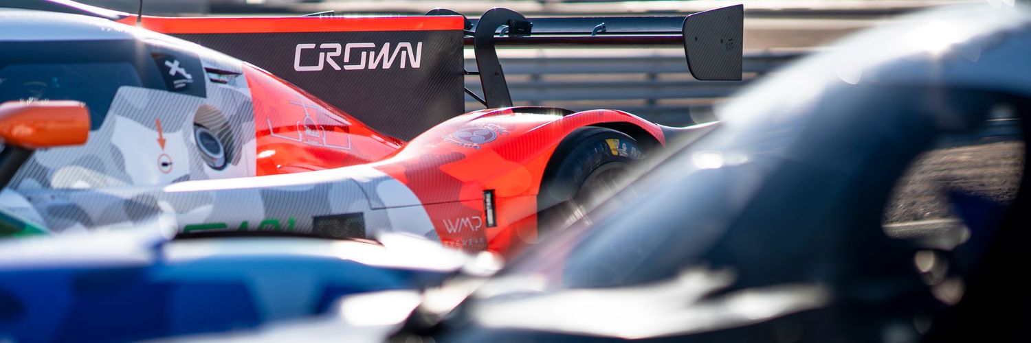 Detail shot of racing car bodywork showing Crown branding among multiple vehicles.
