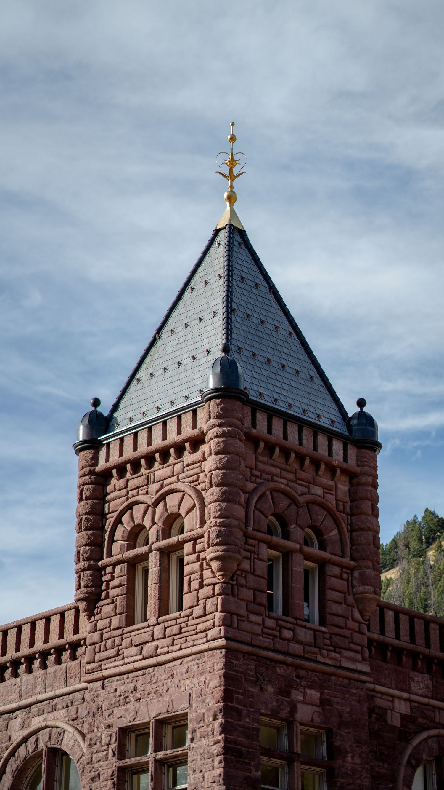 Stone castle tower with ornate architectural details against cloudy sky.