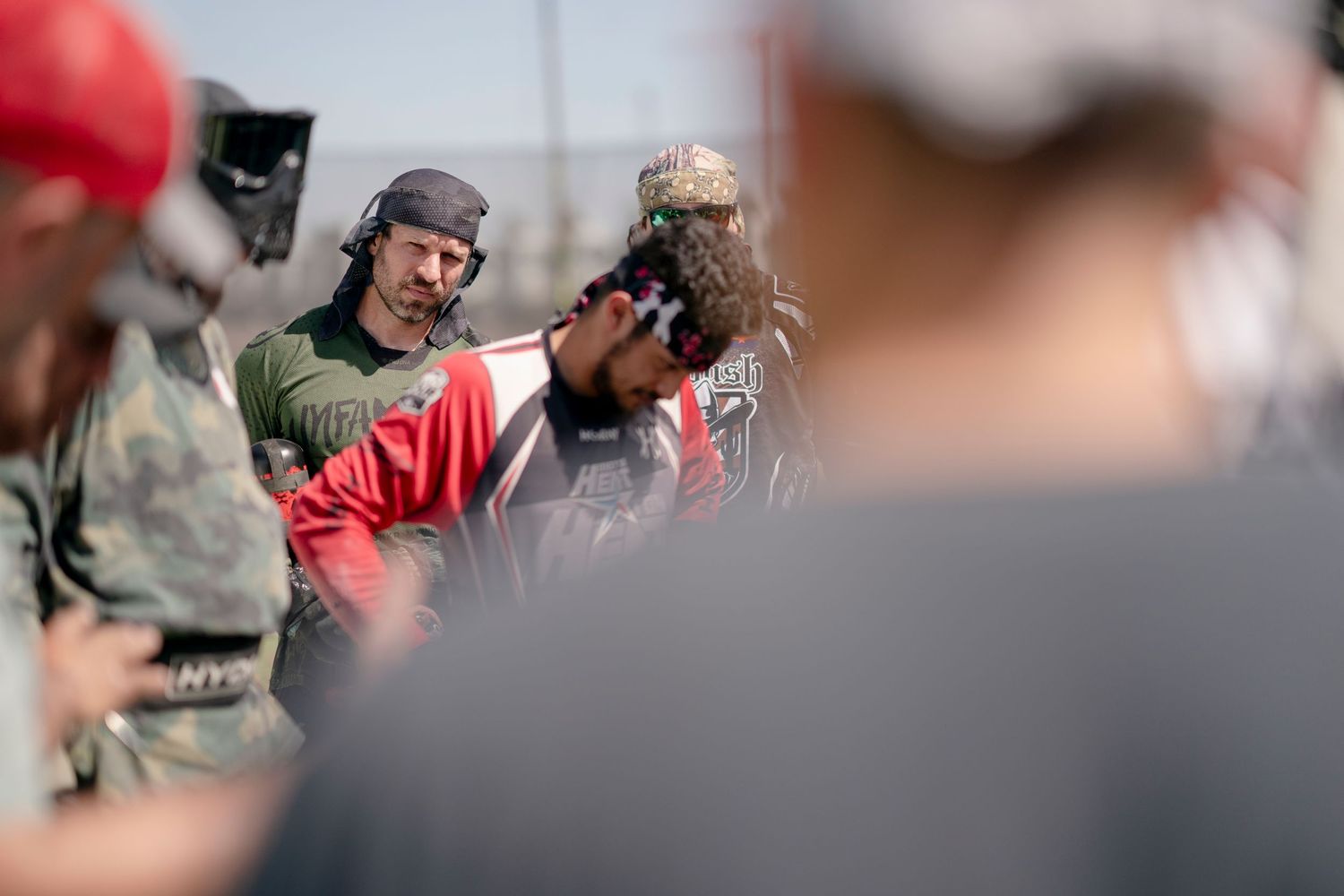 Players huddled together during paintball tournament briefing.