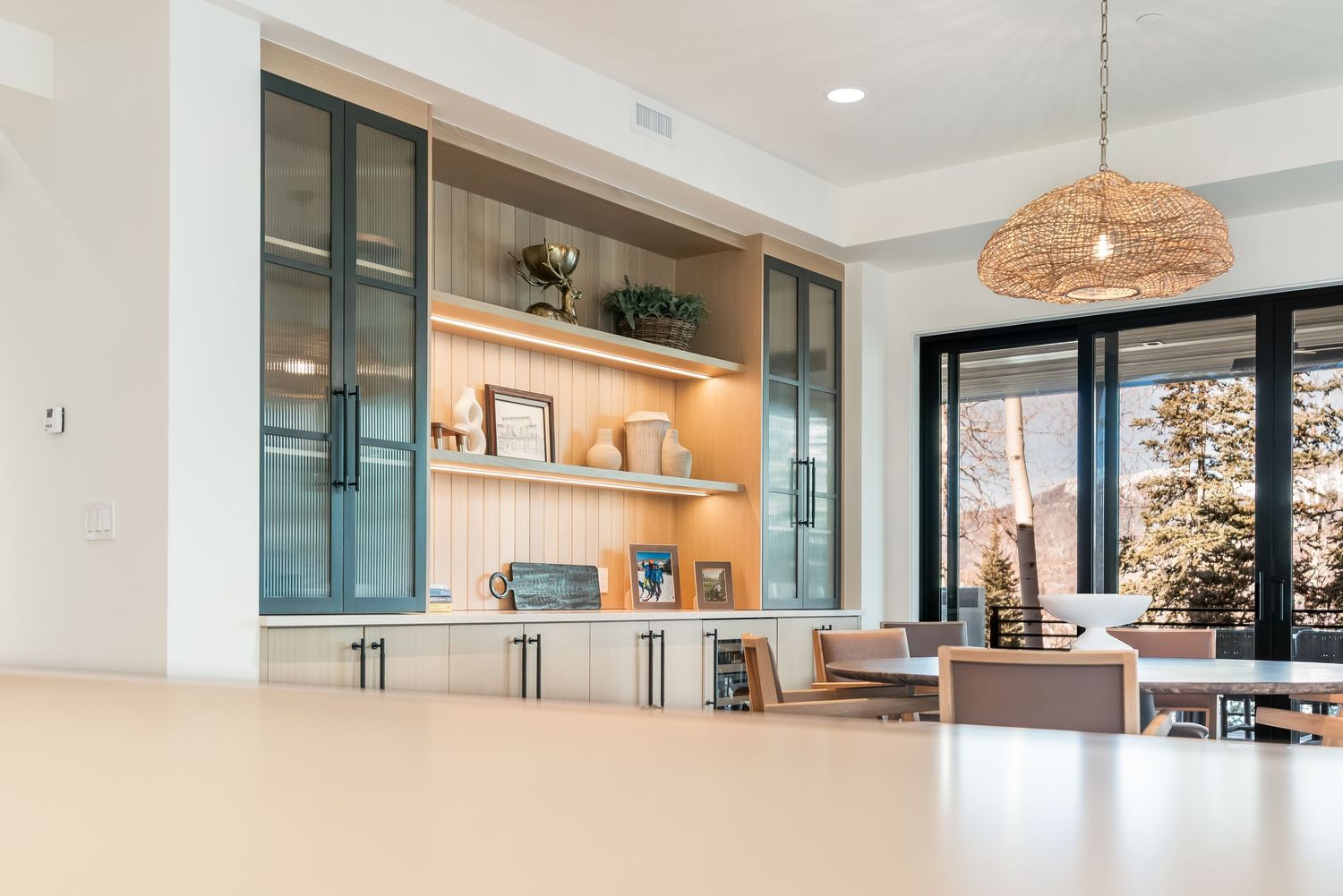 Open concept kitchen and living space with white walls, pendant lighting, and mountain views through large windows.