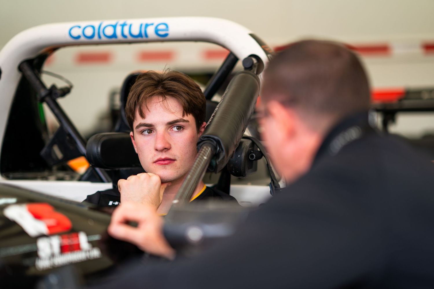Racing team members discussing strategy and preparations in the garage area.