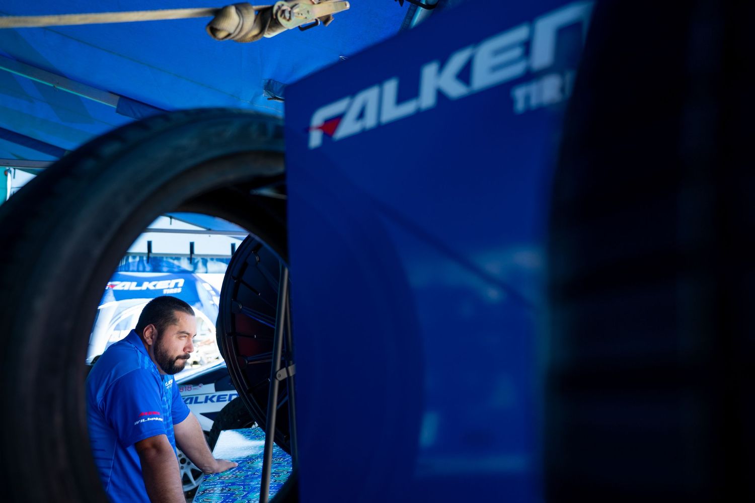A technician works beside Falken Tire branding in a professional racing pit area.