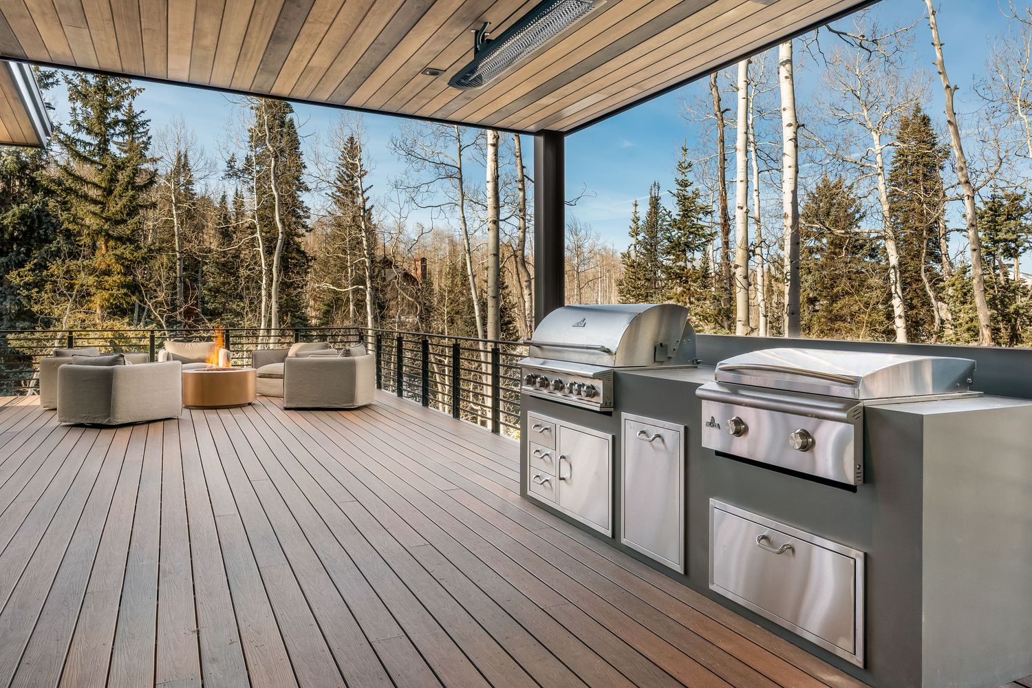 Spacious outdoor deck with built-in kitchen features and mountain forest views in the background.