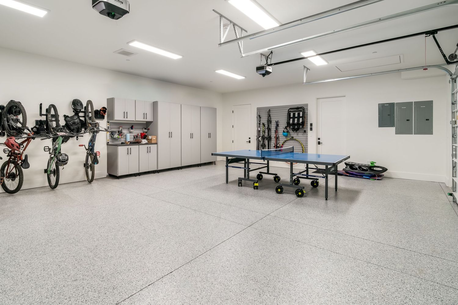 A clean, modern fitness facility with white walls and rubber flooring features exercise equipment and training stations.