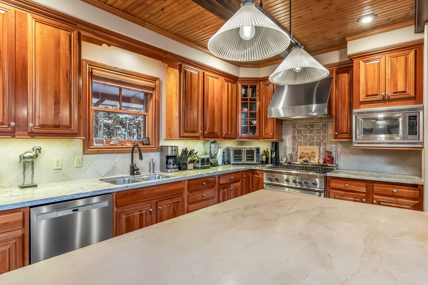 Modern kitchen with rich wood cabinets, stainless steel appliances, and granite countertops in panoramic view.