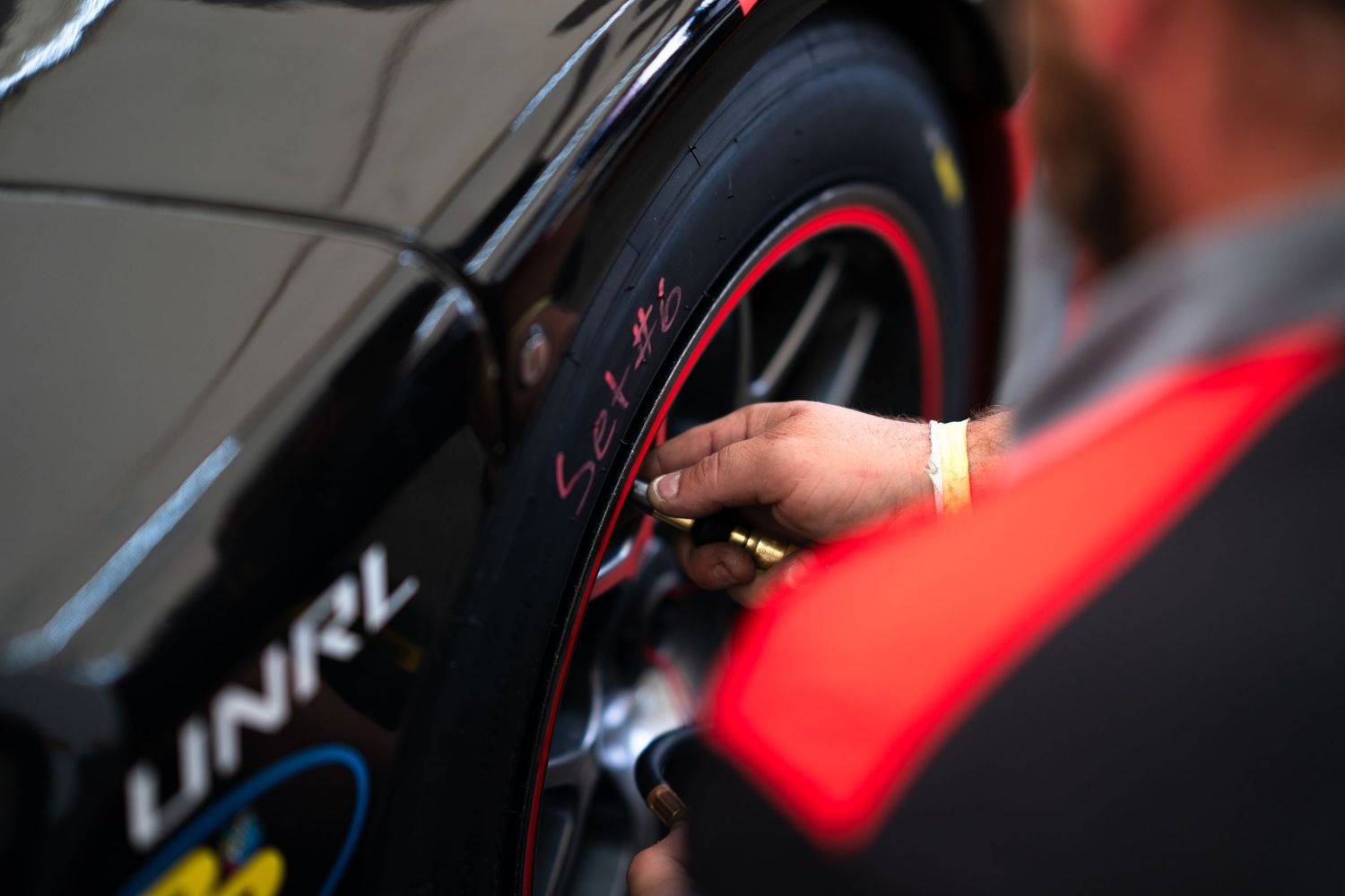 Close-up detail of racing car tire and suspension components during technical inspection.