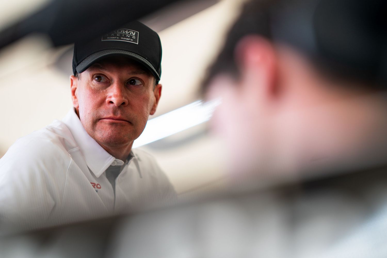 Racing team members focus intently during pit operations under a covered service area.