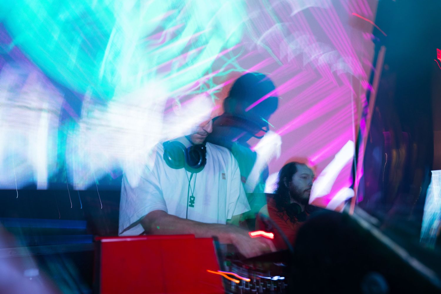 Vibrant neon blue and pink lights create abstract streaks and patterns in a dark nightclub atmosphere.