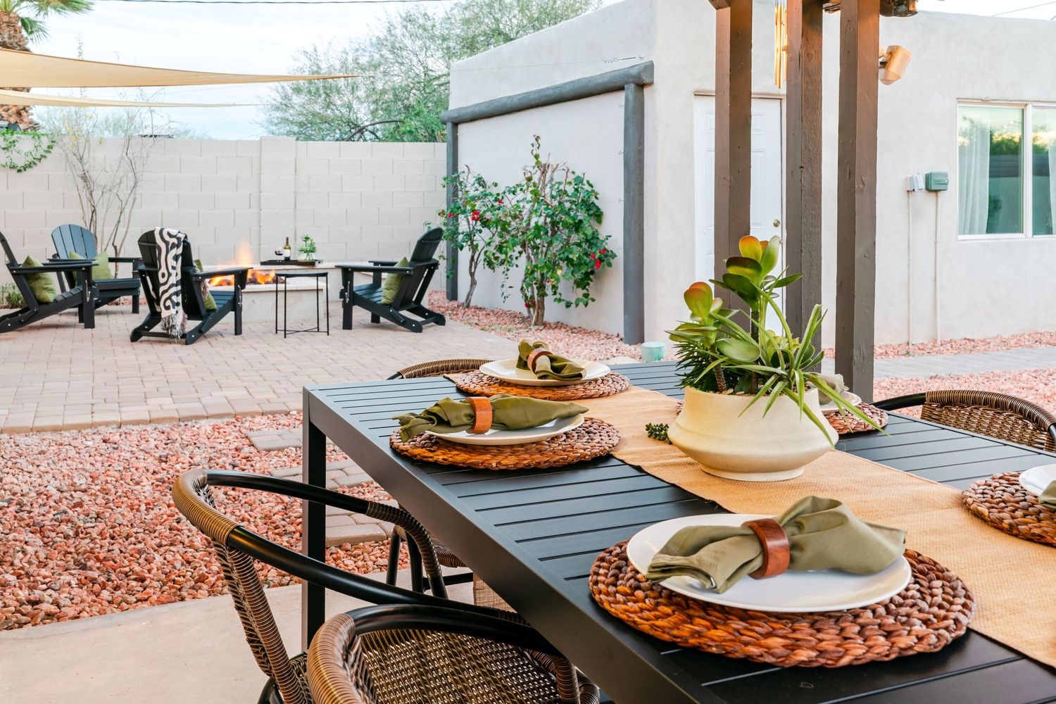 A modern outdoor patio space with woven placemats and table settings against a desert landscape background.