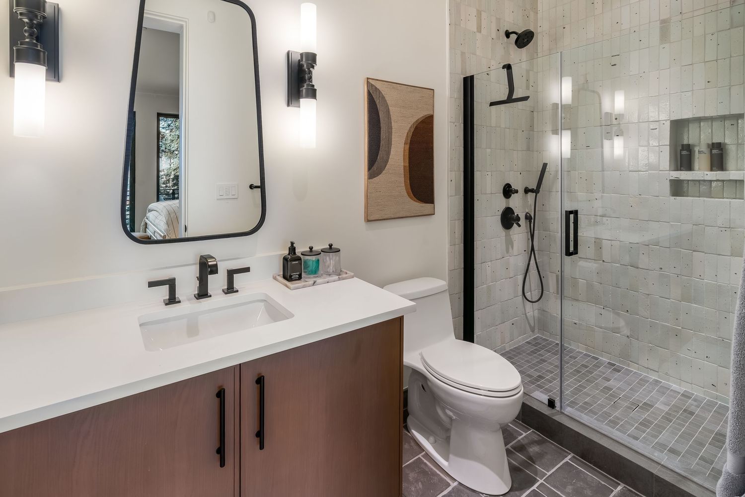 Sleek bathroom with marble tile, black fixtures, glass shower enclosure and modern amenities.