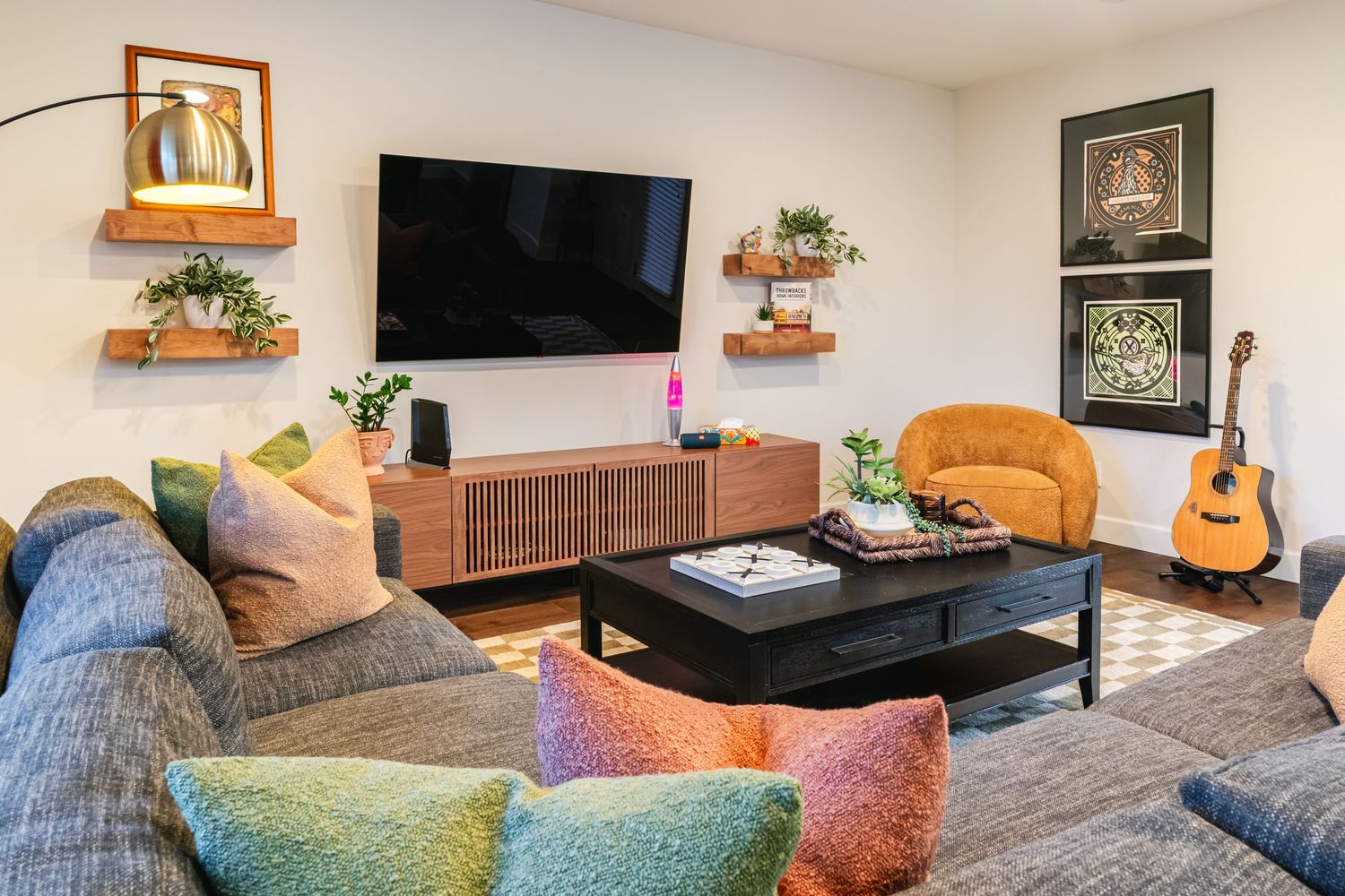 Living room with comfortable seating, TV, guitar, and decorative accents in warm earth tones.