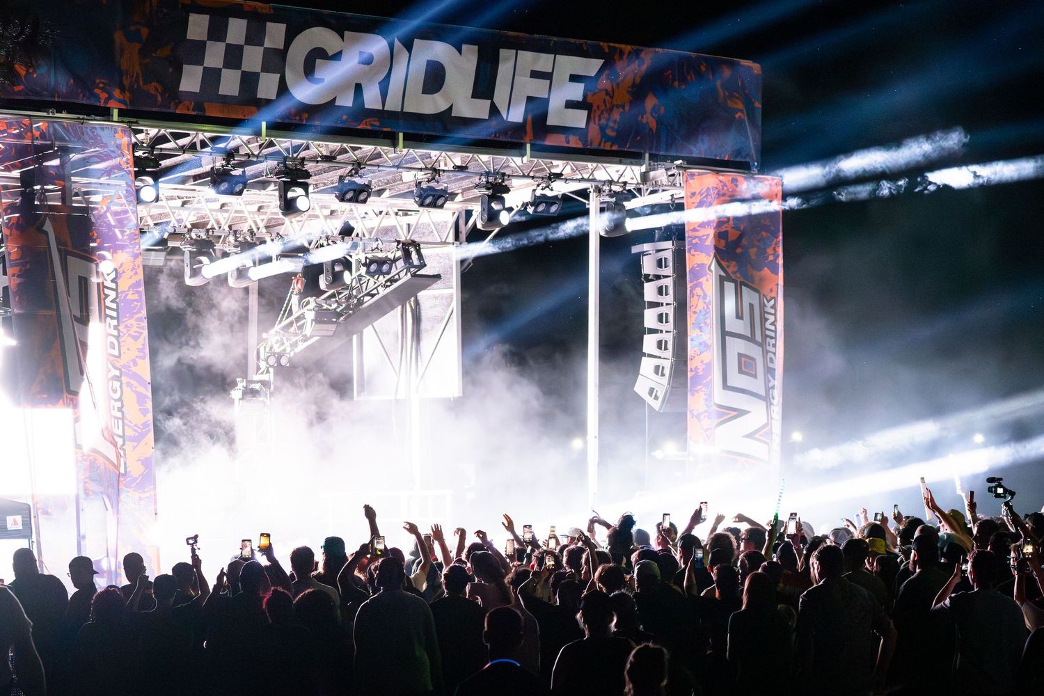 GRIDLIFE festival crowd cheering under vibrant stage lights with fog effects at an outdoor motorsport music event.