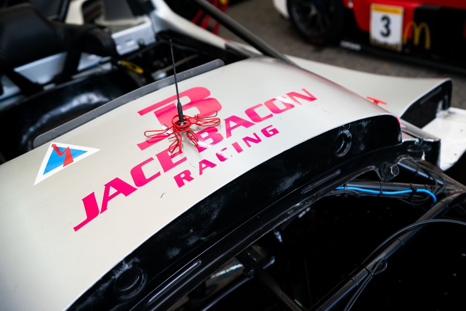 Close-up detail of race car bodywork showing sponsor decals and racing numbers.