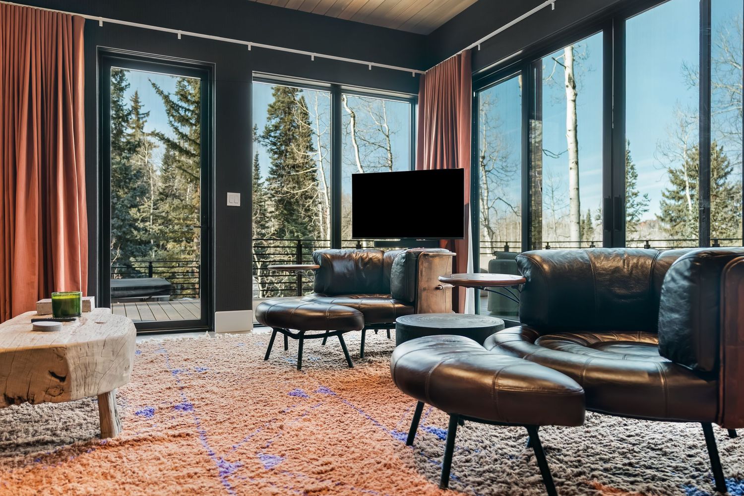 Living room with floor-to-ceiling windows showcases panoramic forest views and contemporary furnishings.