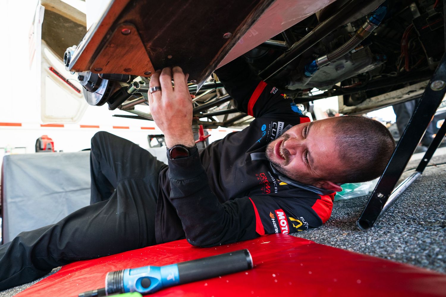 Close-up view of racing car interior showing driver adjusting controls and equipment.