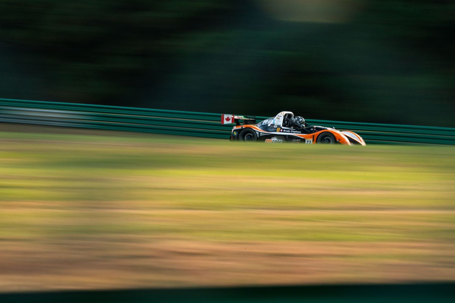 Race car in motion blur speeds through a corner against blurred green background.