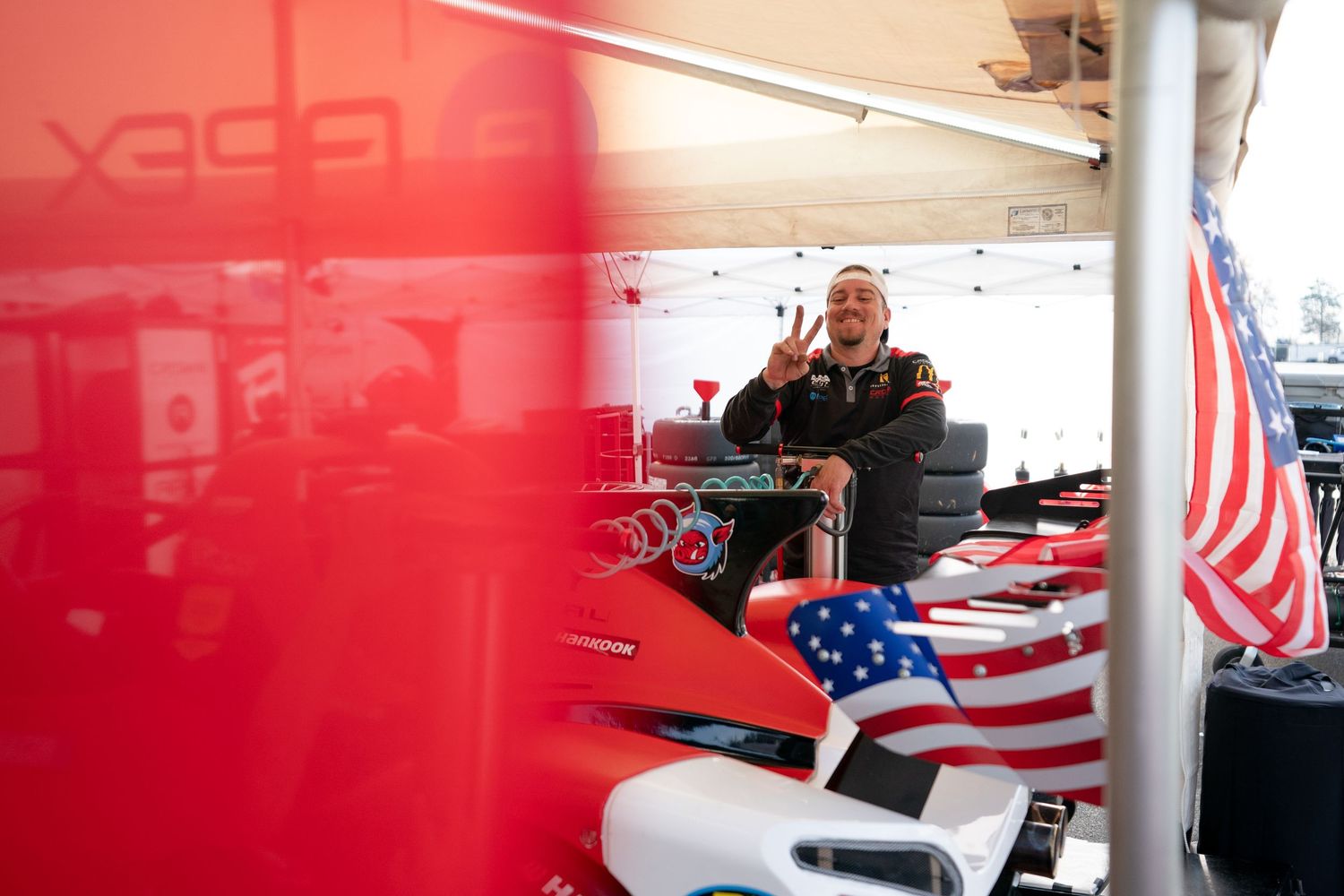 Red racing team garage interior with American flag displayed prominently.