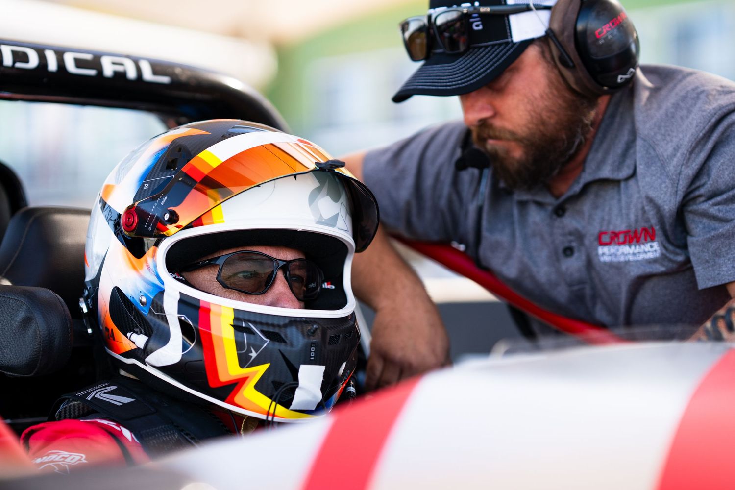 Close-up view of racing helmet and car cockpit details during track day preparations.