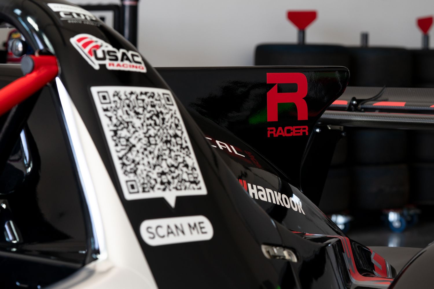 Multiple QR codes displayed on black racing equipment or vehicle parts in low lighting conditions.