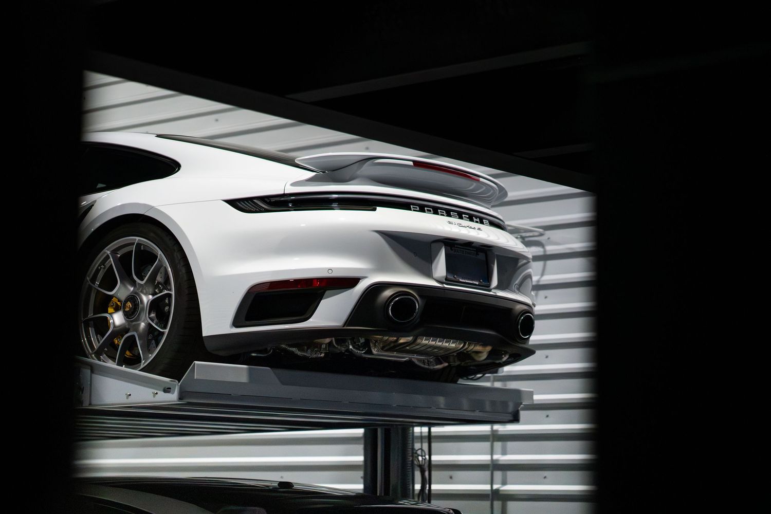 Detail shot of a white luxury vehicle against dark background with dramatic side lighting.