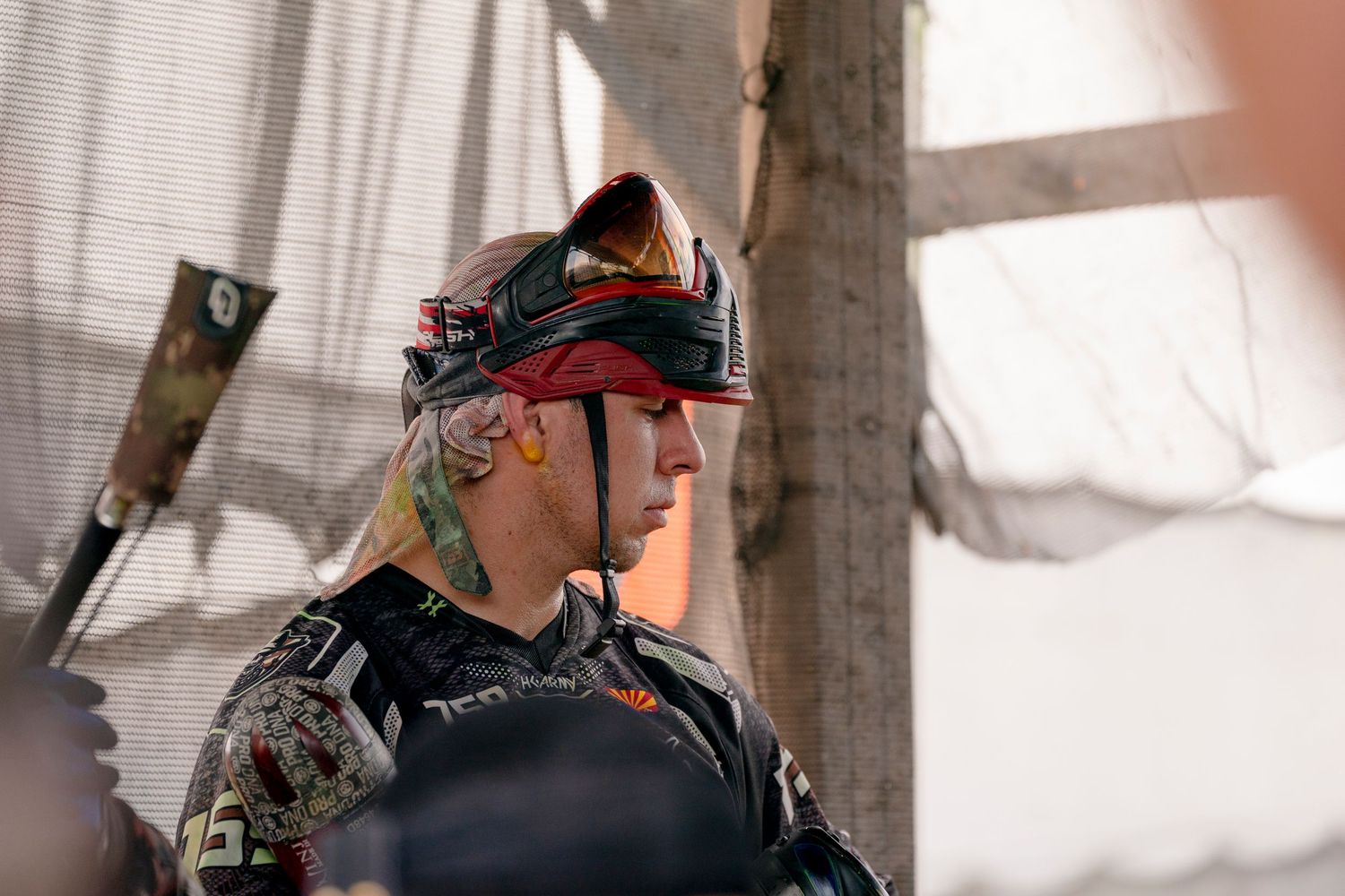 Paintball competitor in protective headgear and tactical gear during game.