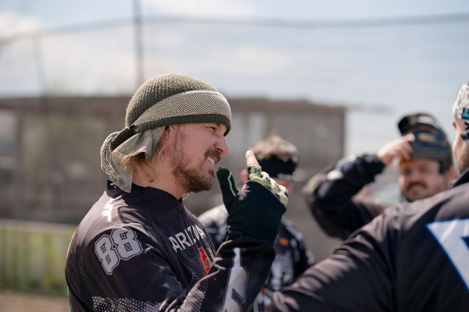 Paintball team member communicating with teammates during game break.