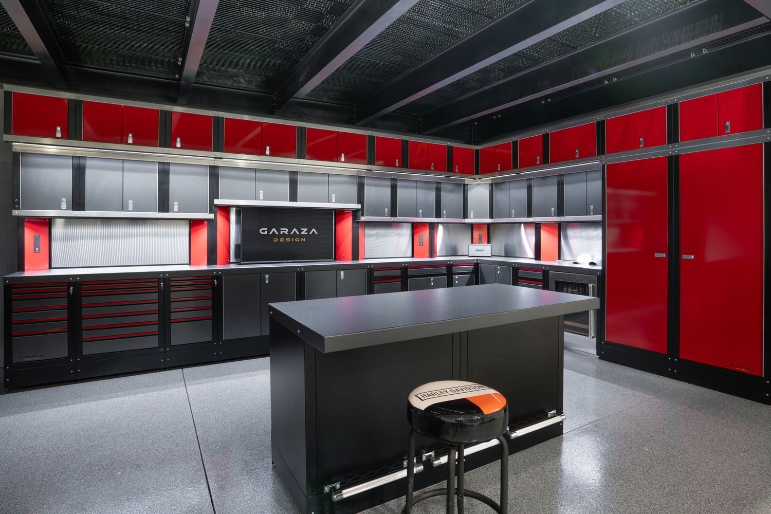 Modern garage workspace with red accent walls, black cabinets, and central workbench island.