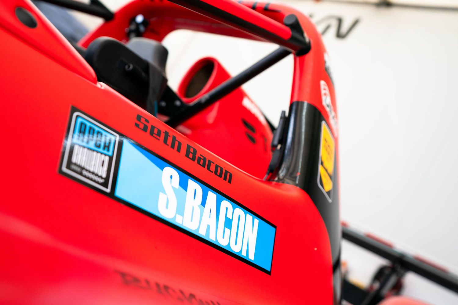 Close-up of racing decals and branding on a red race car body panel.