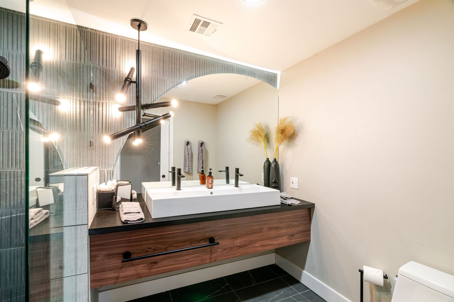 Modern bathroom remodel featuring dark wood vanity, pendant lights, and white subway tile backsplash.