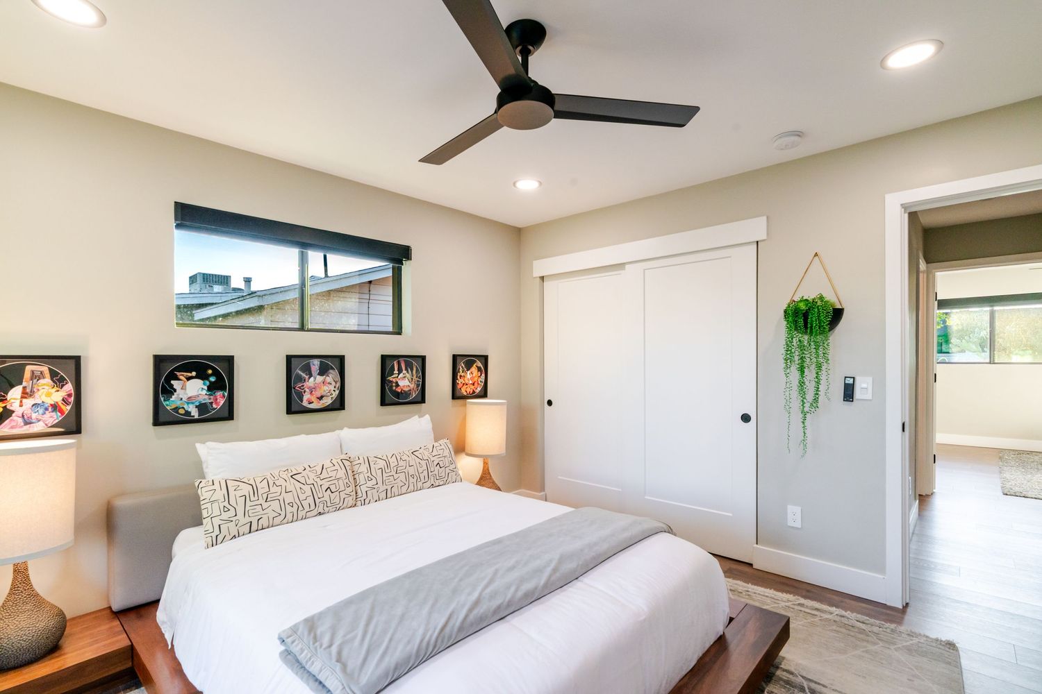 Contemporary bedroom with ceiling fan, recessed lighting, and large windows offering natural light.
