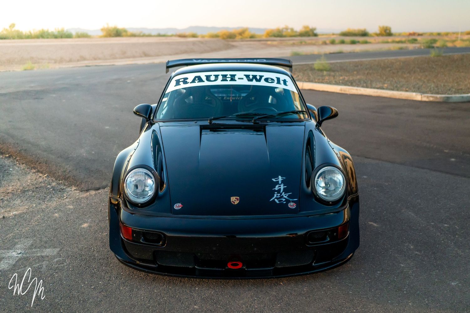Black Porsche 911 RWB sports car with custom bodywork photographed at sunset.
