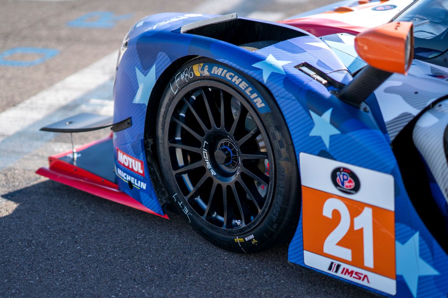 Close-up of American-themed race car wheel and bodywork with number 21.