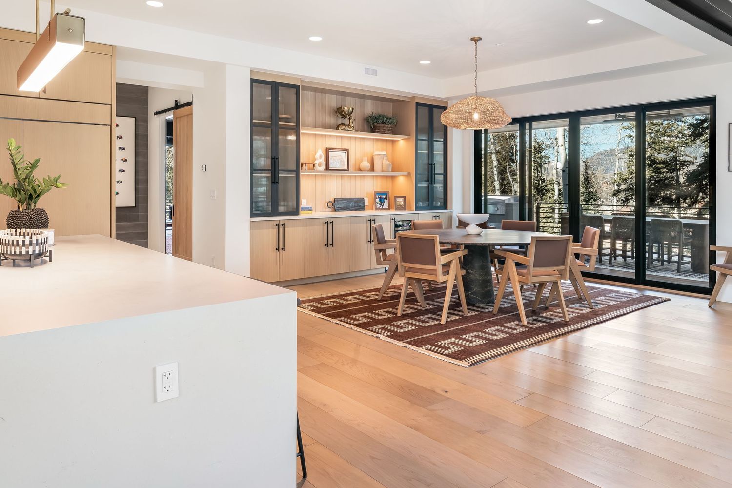 Modern open concept home interior features light hardwood floors and floor-to-ceiling windows flooding space with natural light.