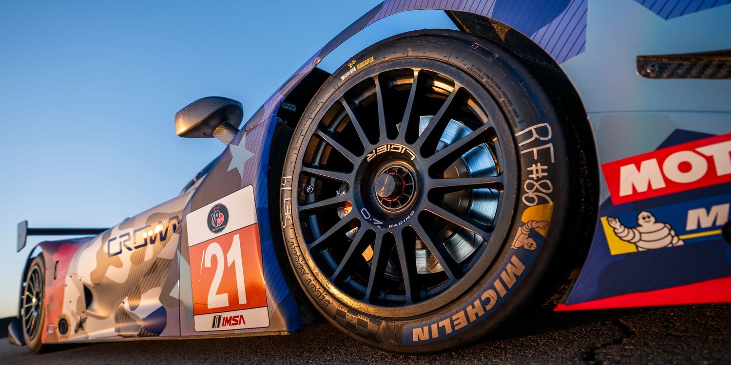 Low angle view of racing prototypes against a sunset desert backdrop at a race circuit.