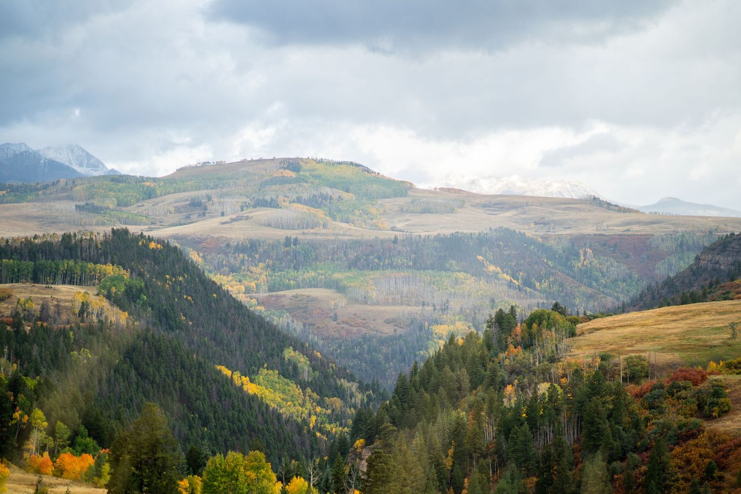 Rolling mountain vista with autumn colors and cloudy sky.
