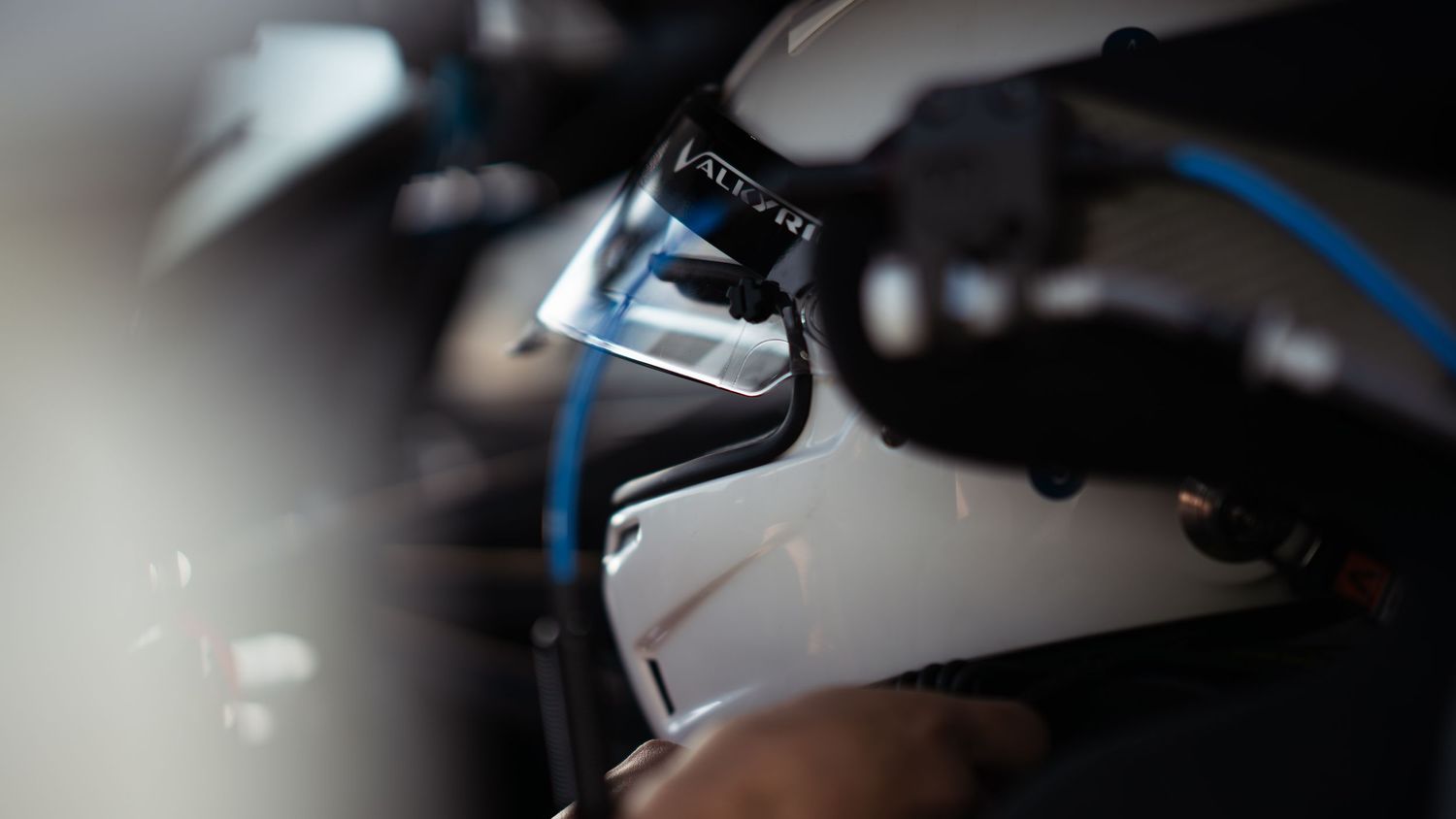 Detail shot of racing car interior focusing on steering wheel and dashboard controls.
