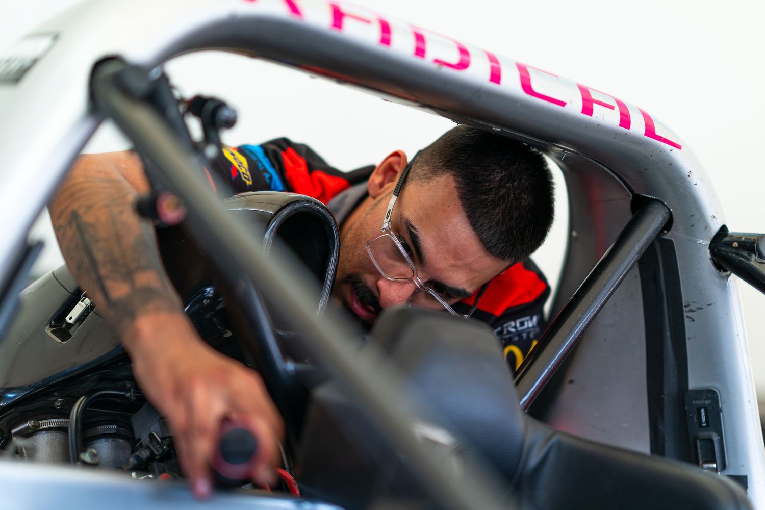 Close-up view of a race car driver adjusting controls inside a Formula 1 cockpit during a pit stop.