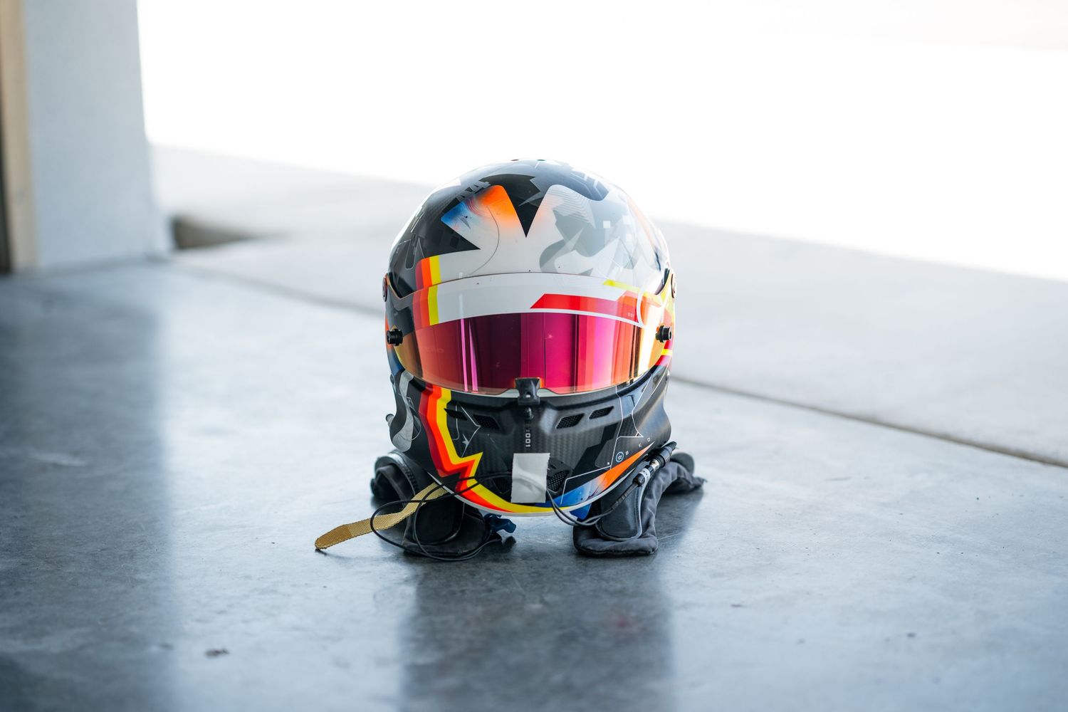 Collection of racing helmets with vibrant designs displayed on a gray surface.