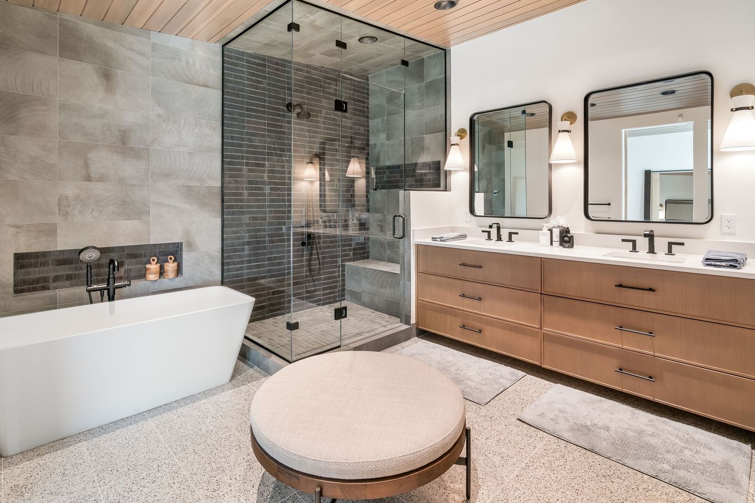 Luxurious bathroom featuring grey tile, floating vanity, and freestanding soaking tub with mountain views.
