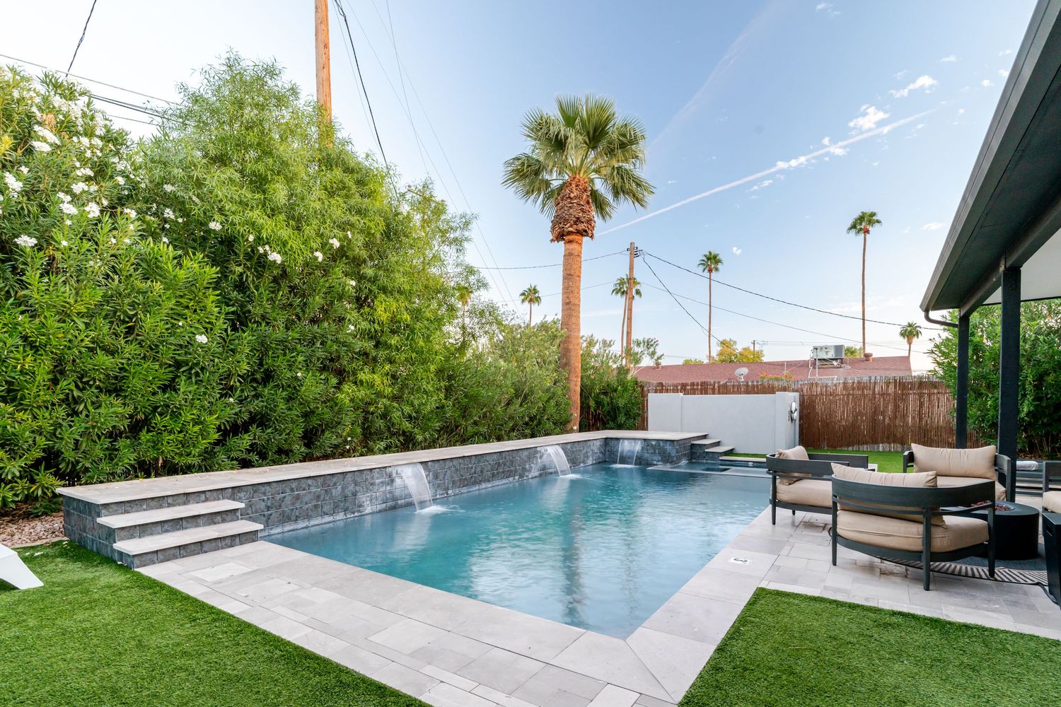 Modern backyard with sleek pool, lounge chairs, and palm trees creating a luxurious outdoor oasis.