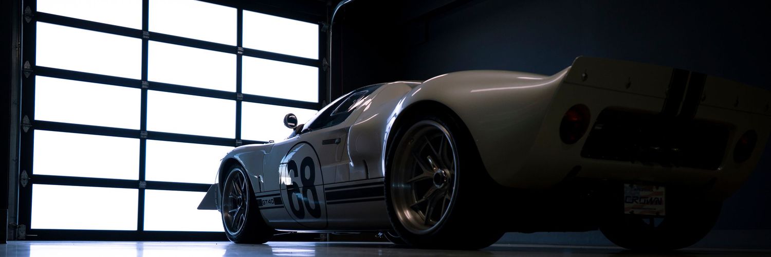 A sleek black luxury car parked in a dimly lit showroom with large windows and dramatic lighting.