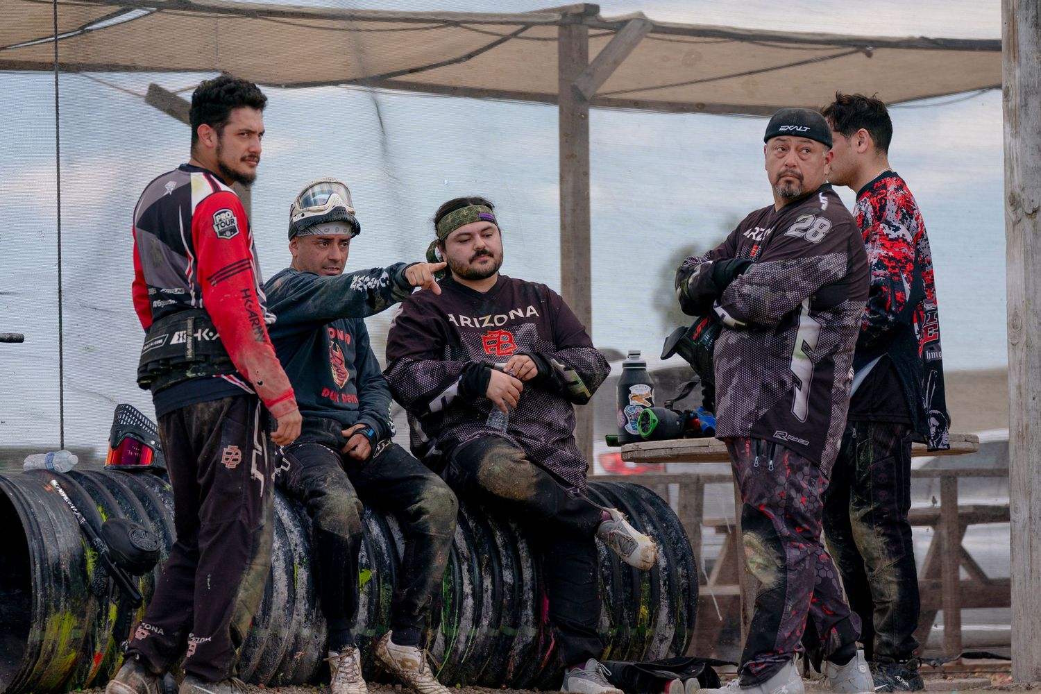 Group of paintball players relaxing and socializing under covered area.