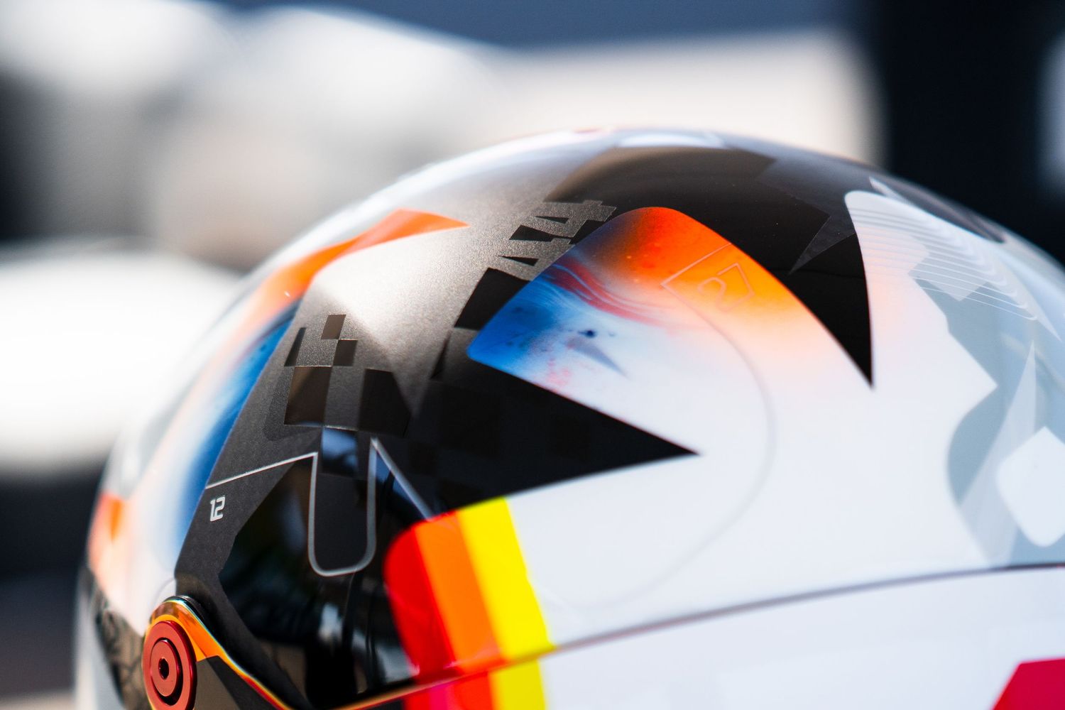 Close-up detail of white racing helmet showing colorful gradient stripe pattern.
