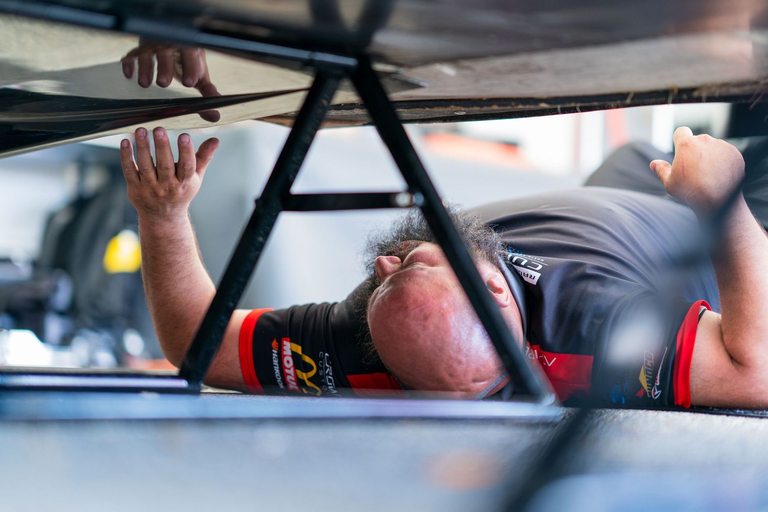 Close-up shots of racing mechanics working on car components in a pit garage.
