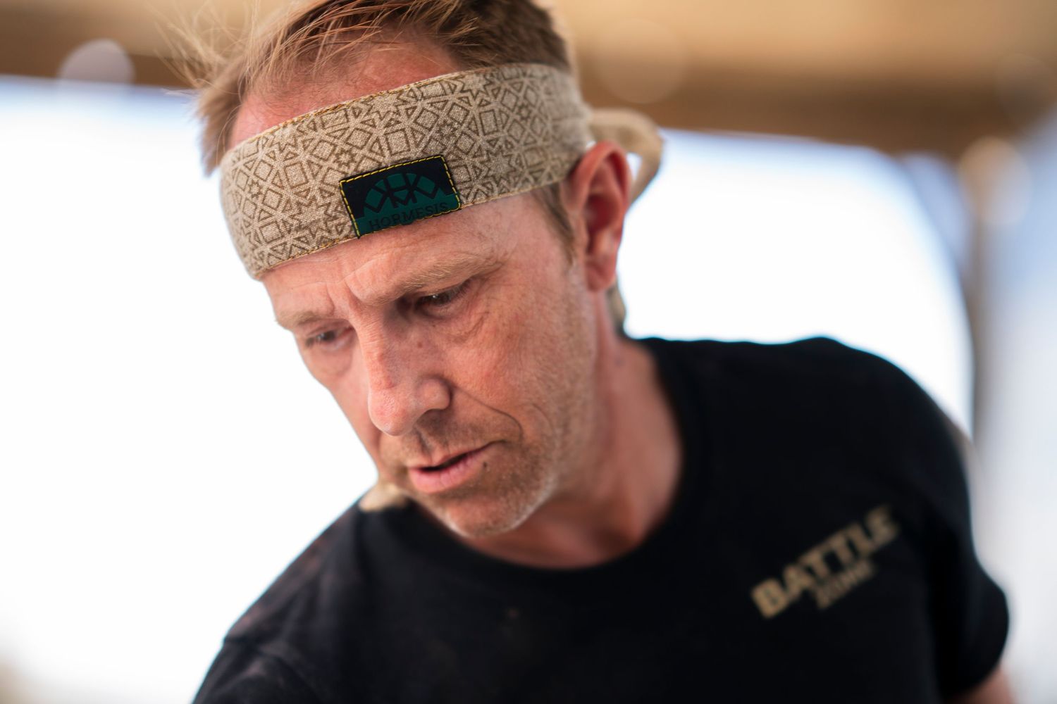 A person wearing a headband and black clothing works intently on a task in a dimly lit setting.