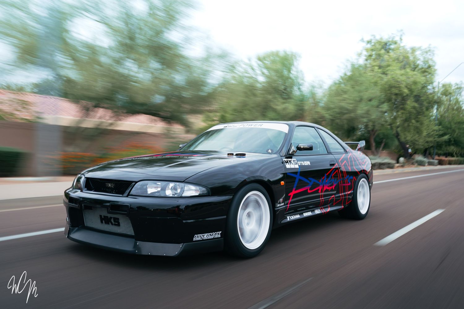 A black lowered sports car shown from multiple angles on a desert road.